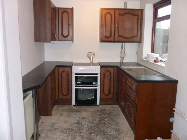 Finished kitchen with dark wood doors and black worktops