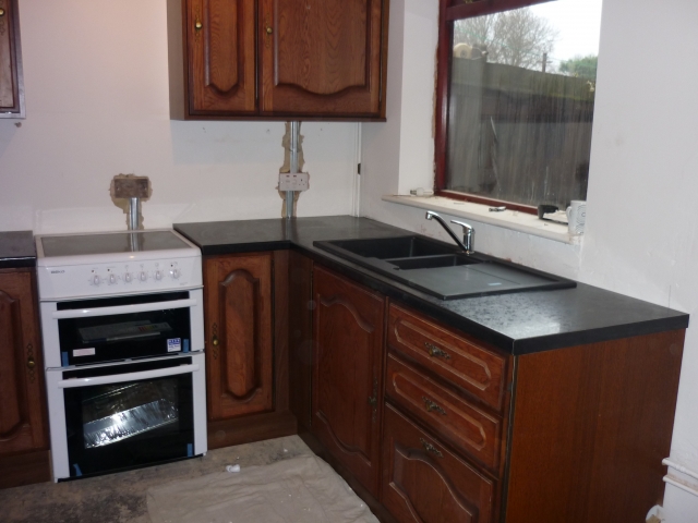 Dark wood kitchen with a black sink under the window