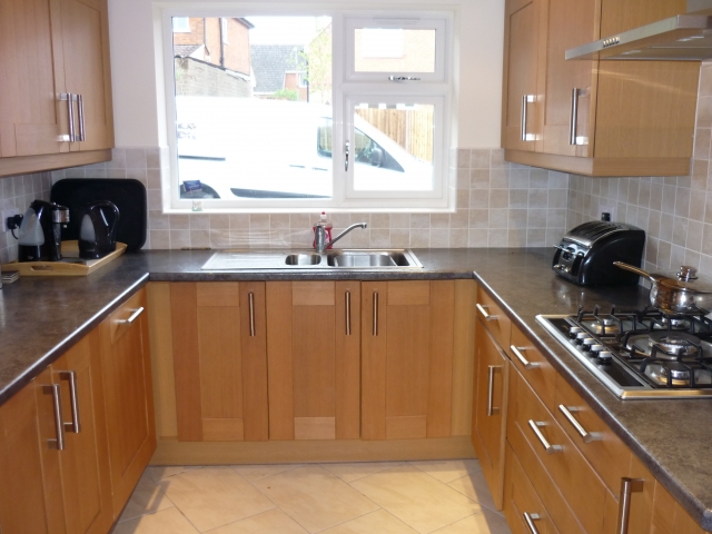 Oak-effect kitchen with a dark worktop and gas hob