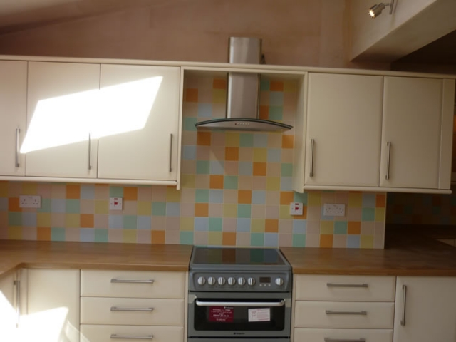 Cooker between cream base units with a tiled splashback
