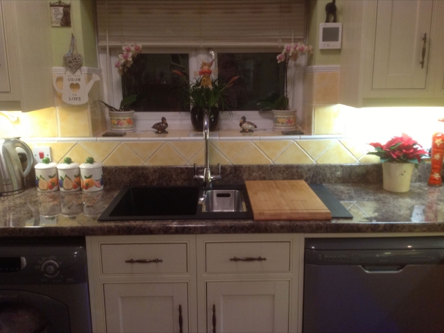 Black sink set into a stone-effect worktop beneath the window